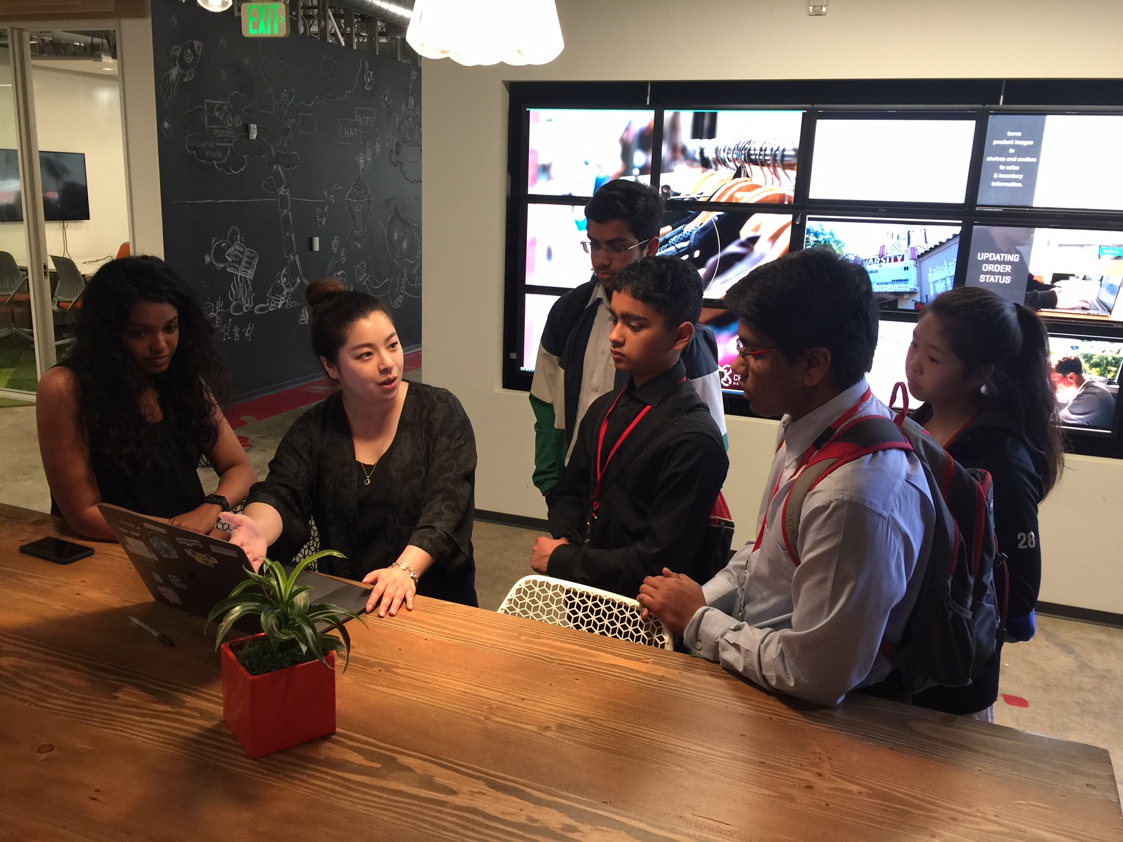 A group of students talking to a woman in an engineering company.