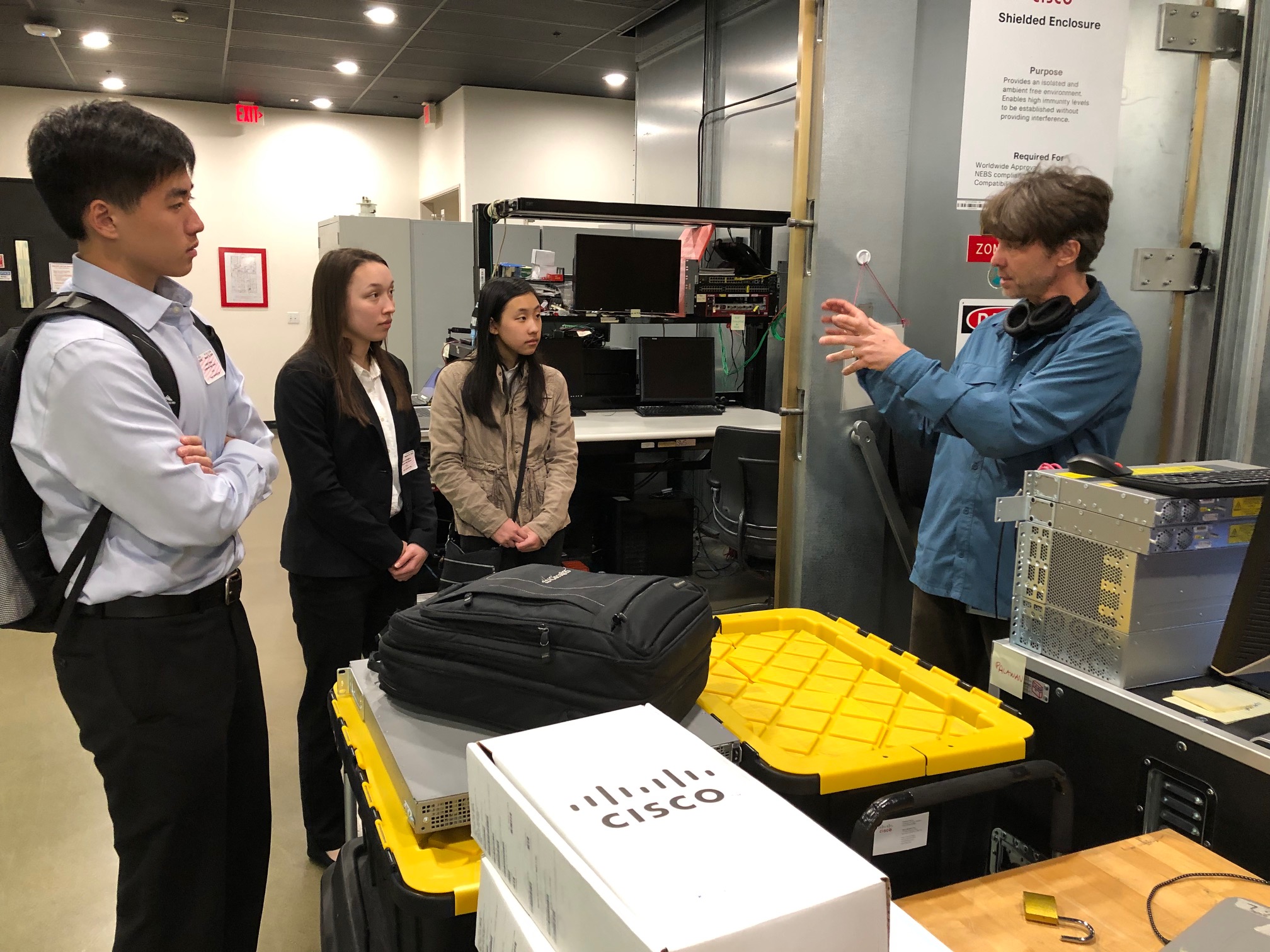 A group of students talking in a Cisco warehouse